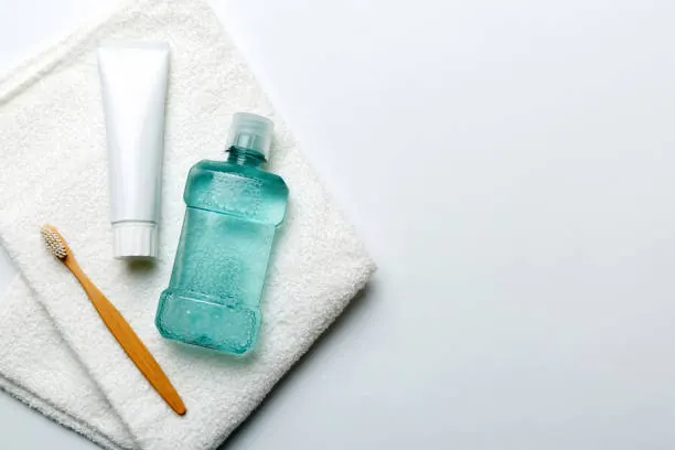 Creme dental, enxaguante bucal e escova de dentes sobre uma toalha branca