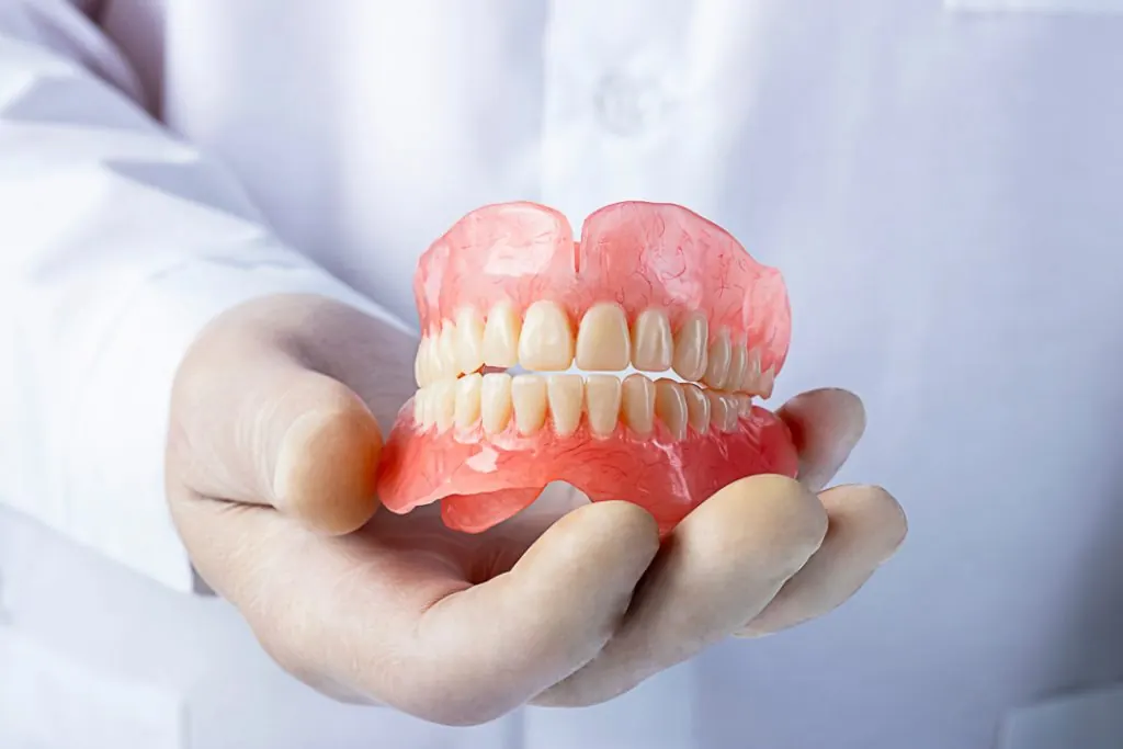 Mão segurando uma prótese dentária total