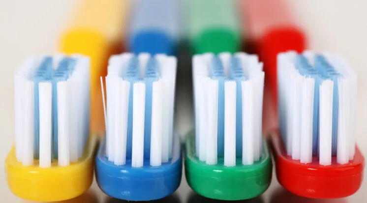 Quatro escovas de dente coloridas com cerdas brancas e azuis lado a lado