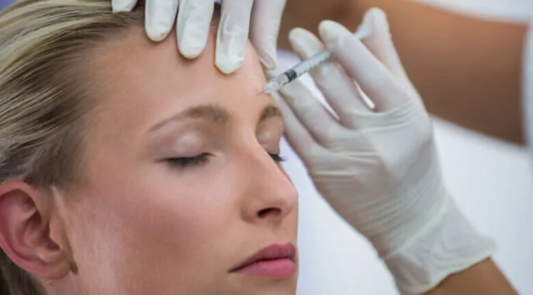 Aplicação de toxina botulínica na testa de uma mulher de olhos fechados