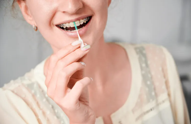 Mulher limpando o aparelho fixo com escova interdental