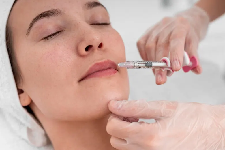 Profissional de luvas aplicando preenchimento nos lábios de uma paciente com seringa