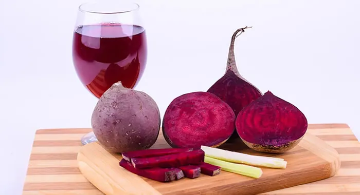 Beterrabas inteiras e um copo de suco de beterraba