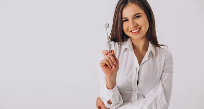 Mulher sorrindo segurando um espelho clínico odontológico
