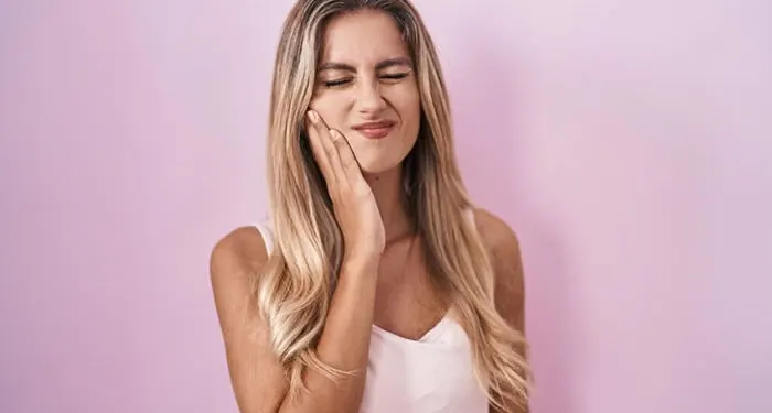 Mulher com a mão no rosto, com expressão de incômodo na boca