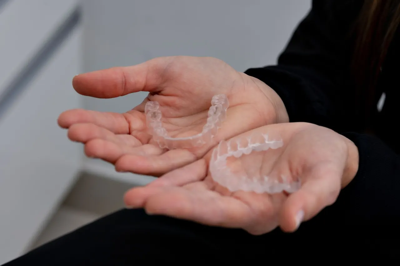Mãos segurando dois alinhadores ortodônticos transparentes