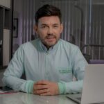 Profissional especialista em Harmonização Orofacial sentado atrás de uma mesa em seu consultório